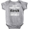 never underestimate an old man who was born in november Baby Onesie